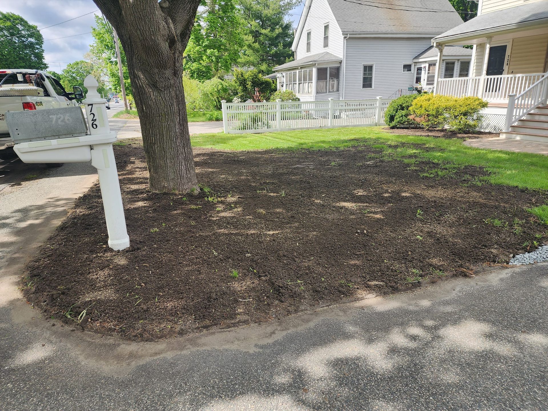 A white truck is parked in front of a house next to a mailbox.