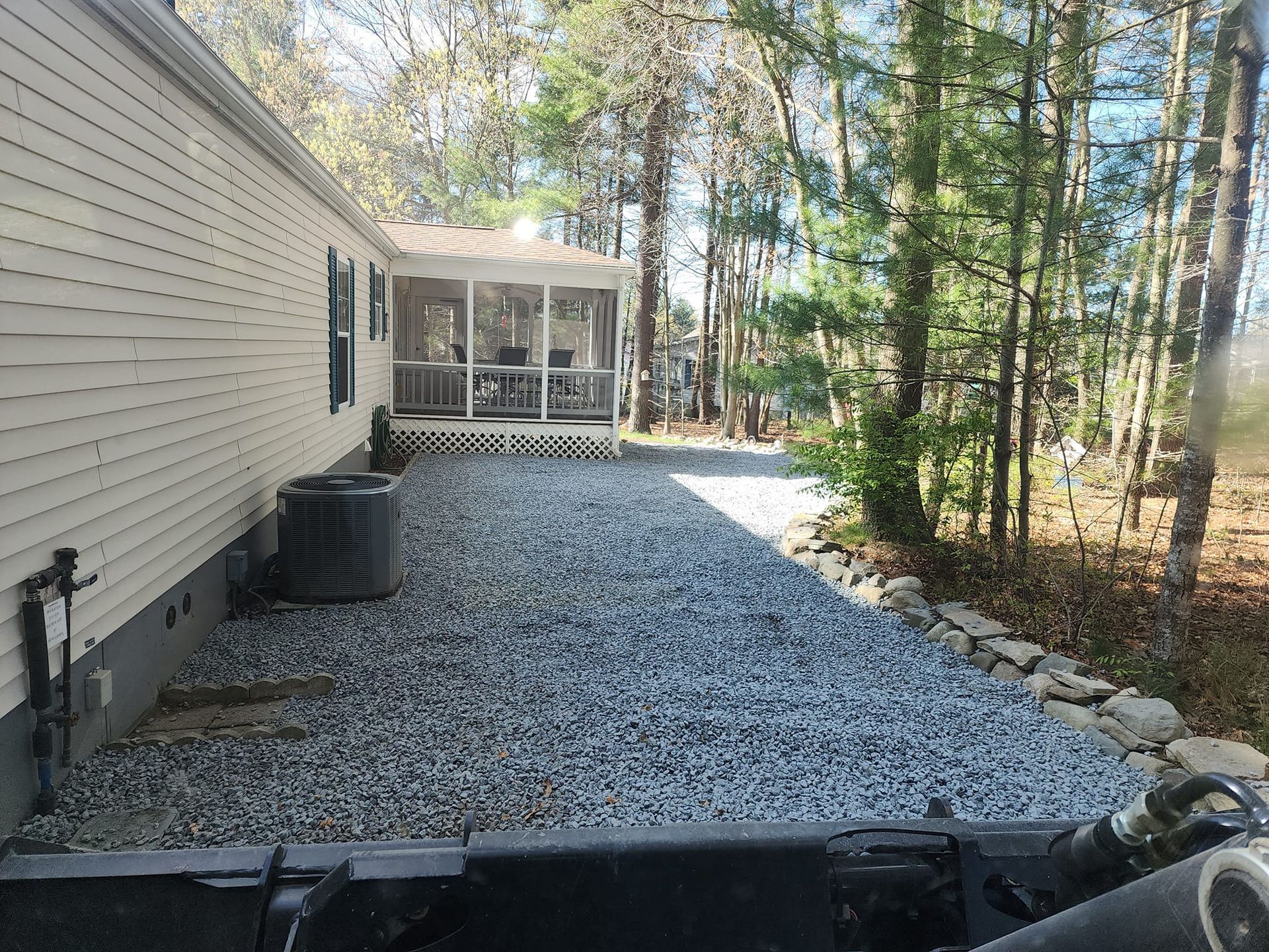 A driveway leading to a mobile home with a screened in porch.