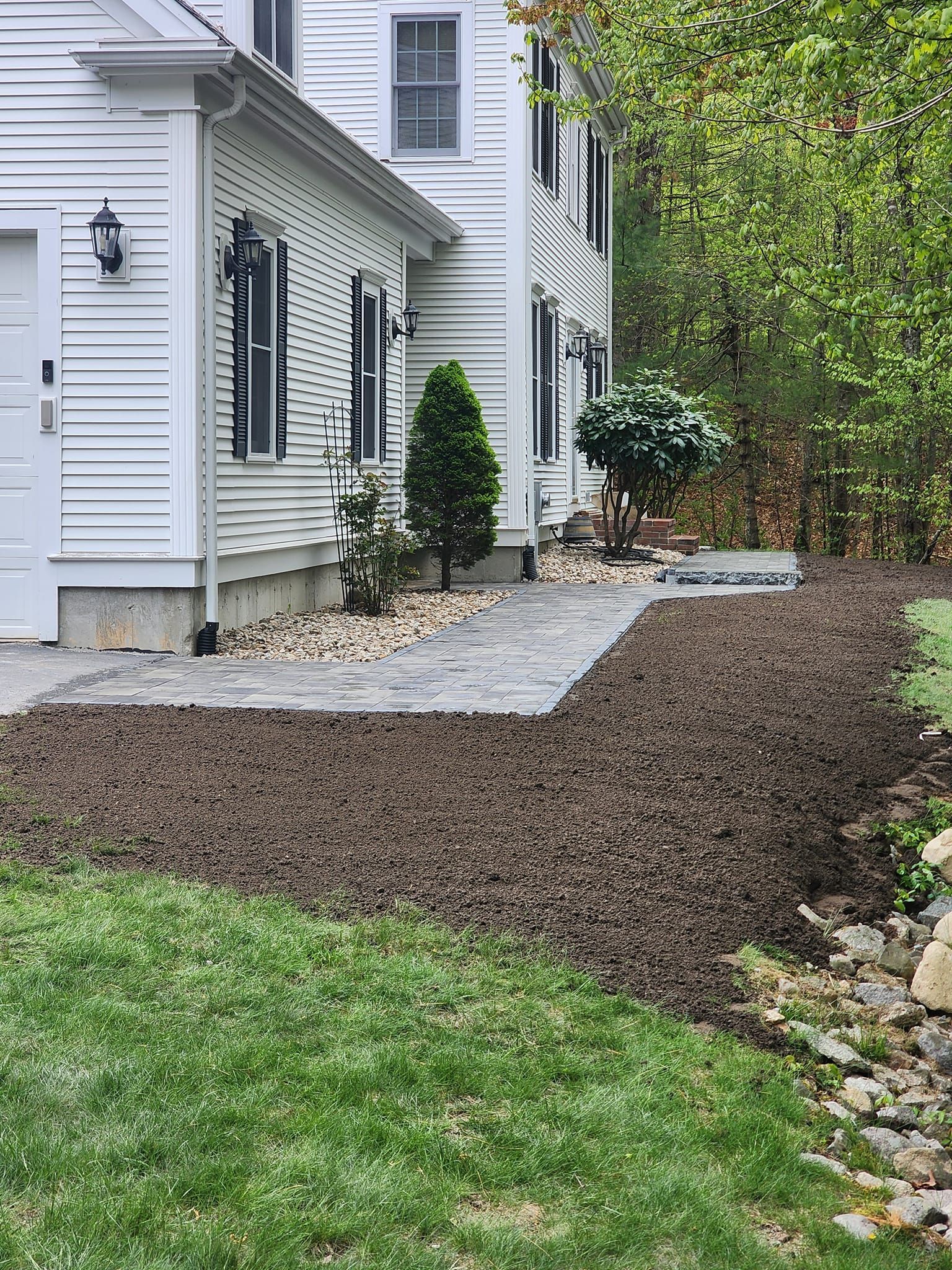 A white house with a patio and a walkway in front of it.