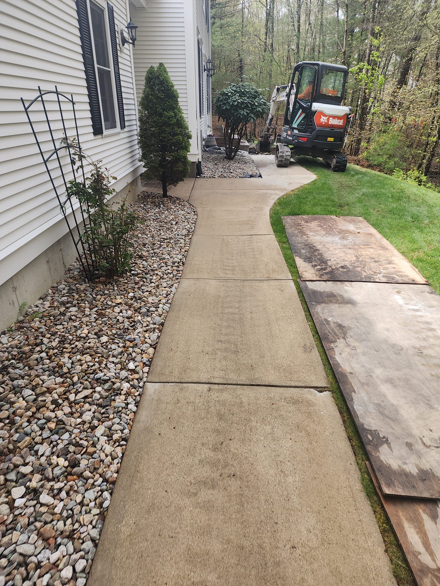 A walkway leading to a house with a bulldozer parked on the side of it.