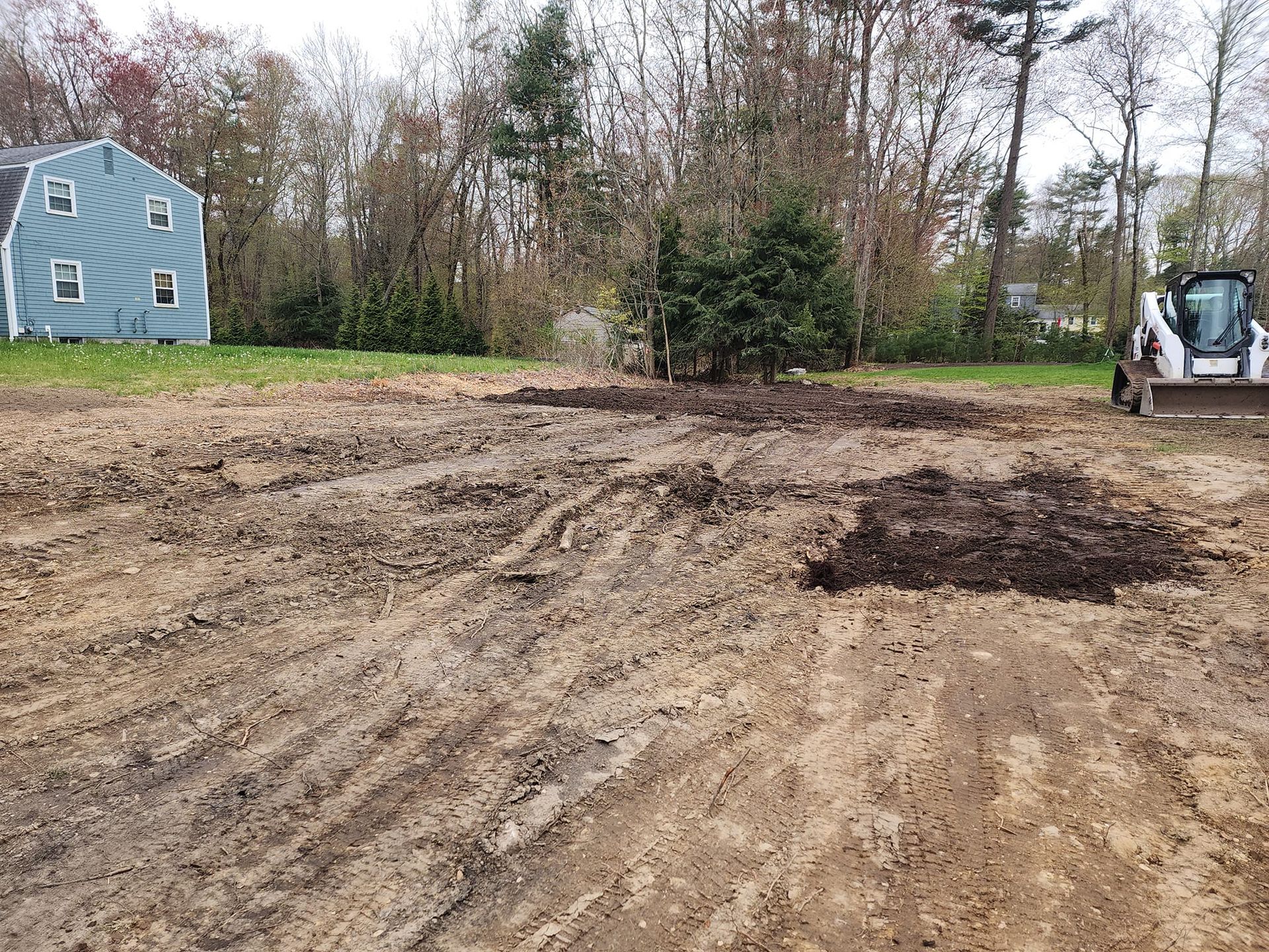 A bulldozer is moving dirt in a field next to a house.