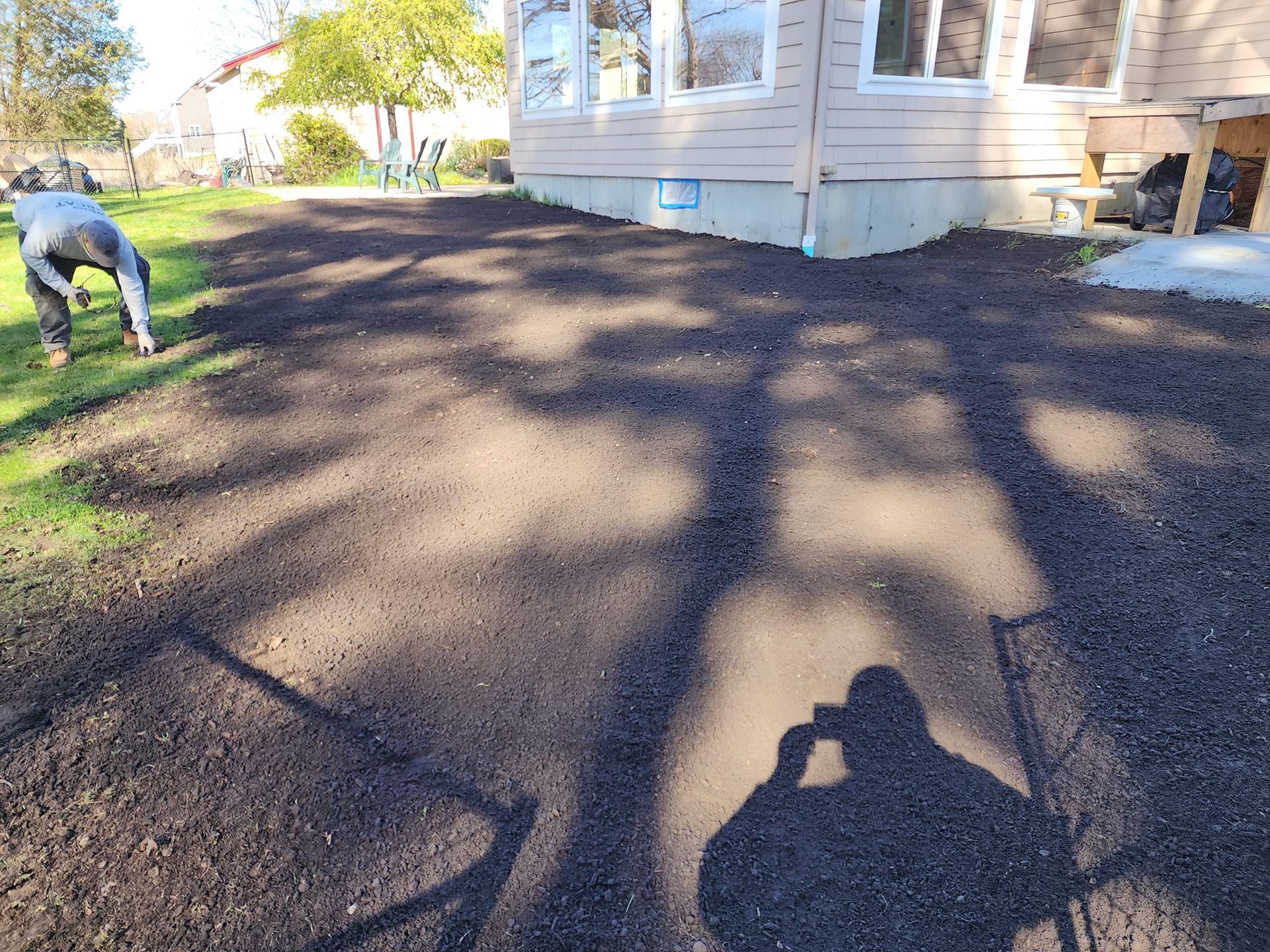 A man is digging in the dirt in front of a house.