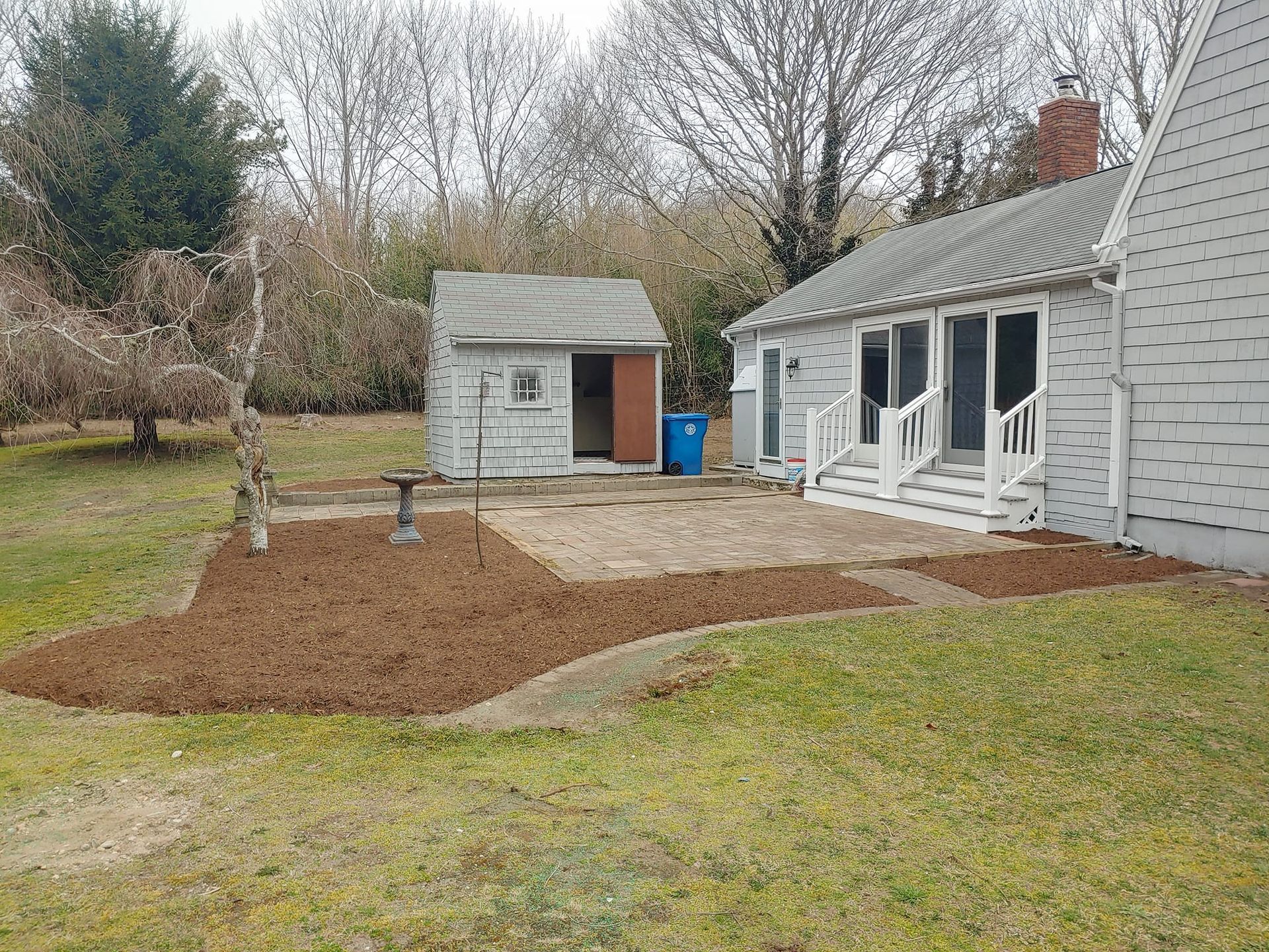 A white house with a small shed in the backyard.