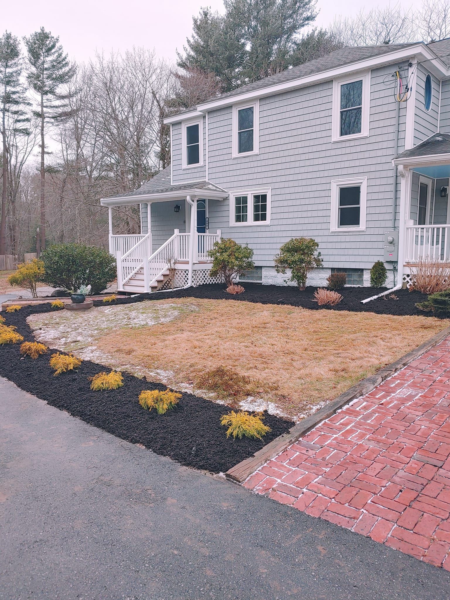 A large white house with a brick driveway in front of it.