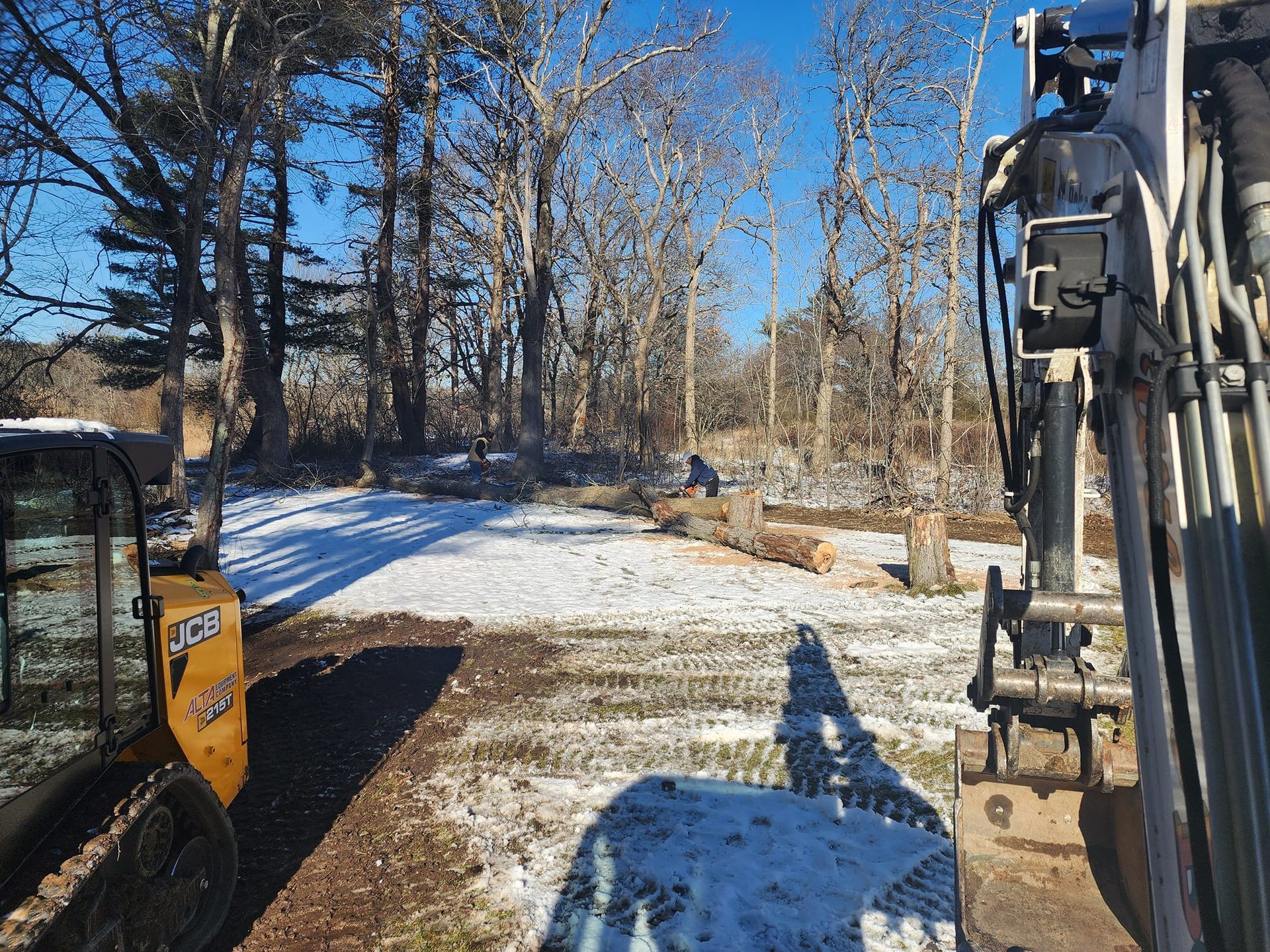 A yellow and white excavator is parked in a snowy field.