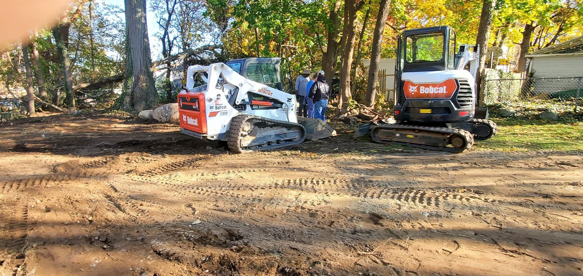 A bulldozer and a small excavator are sitting in a dirt field.