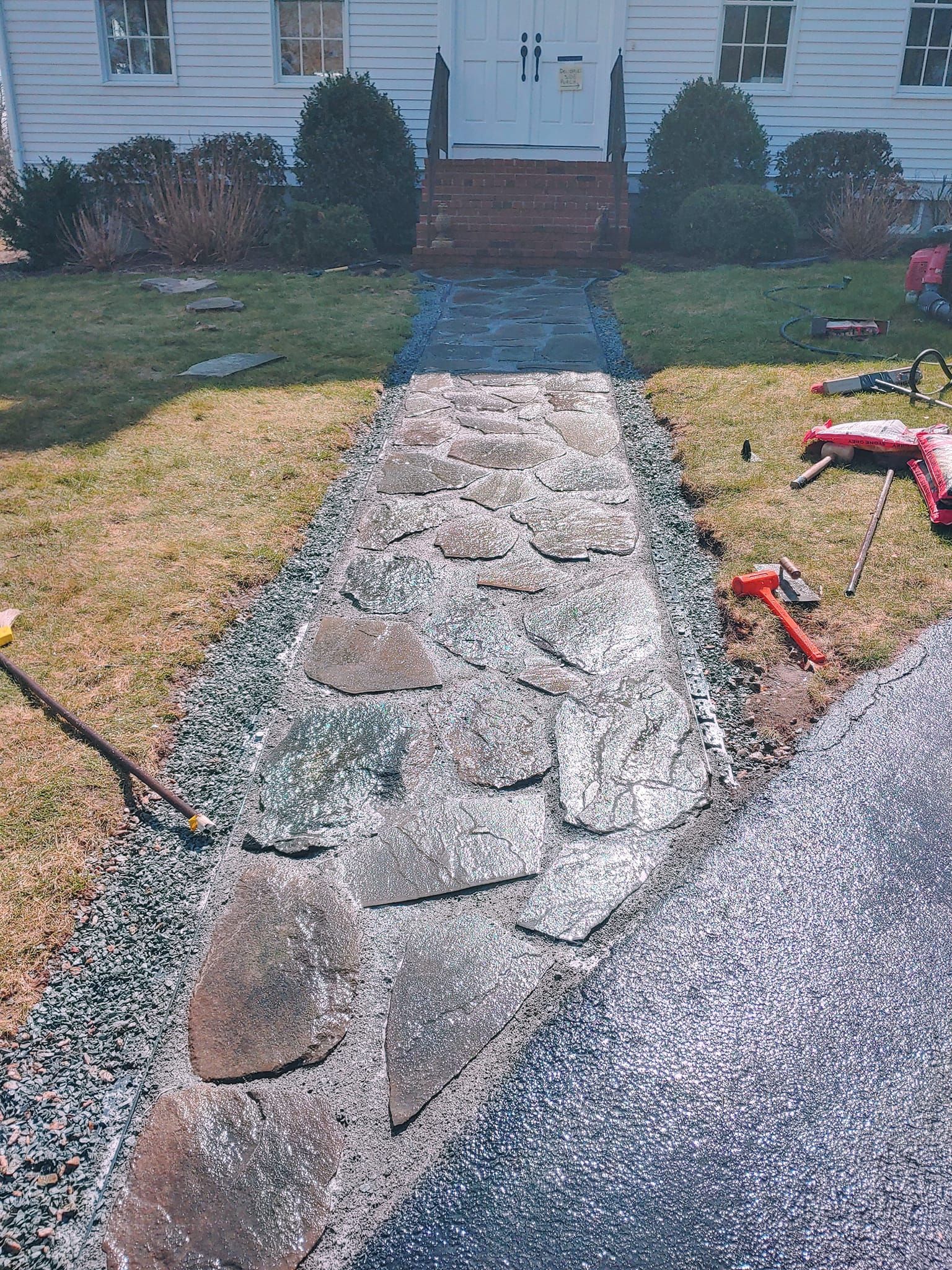 A stone walkway is being built in front of a house.