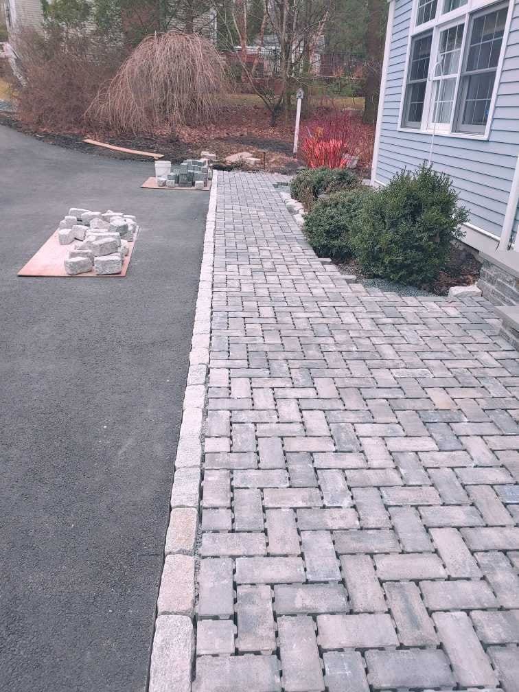 A brick walkway is being built in front of a house.