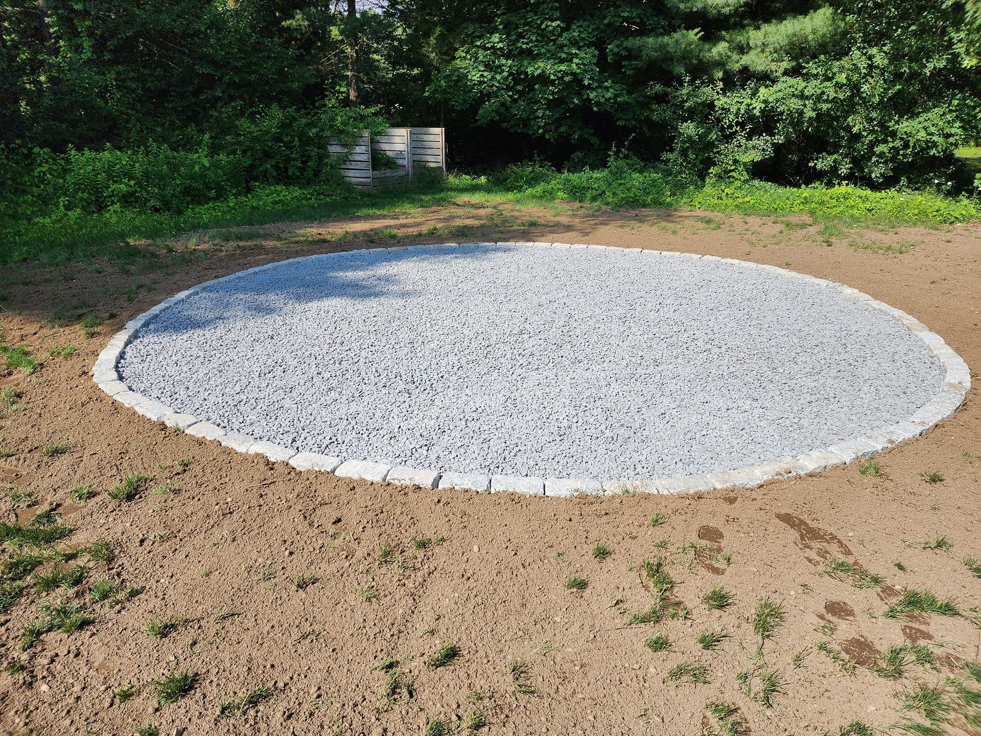 A large circle of gravel is in the middle of a dirt field.