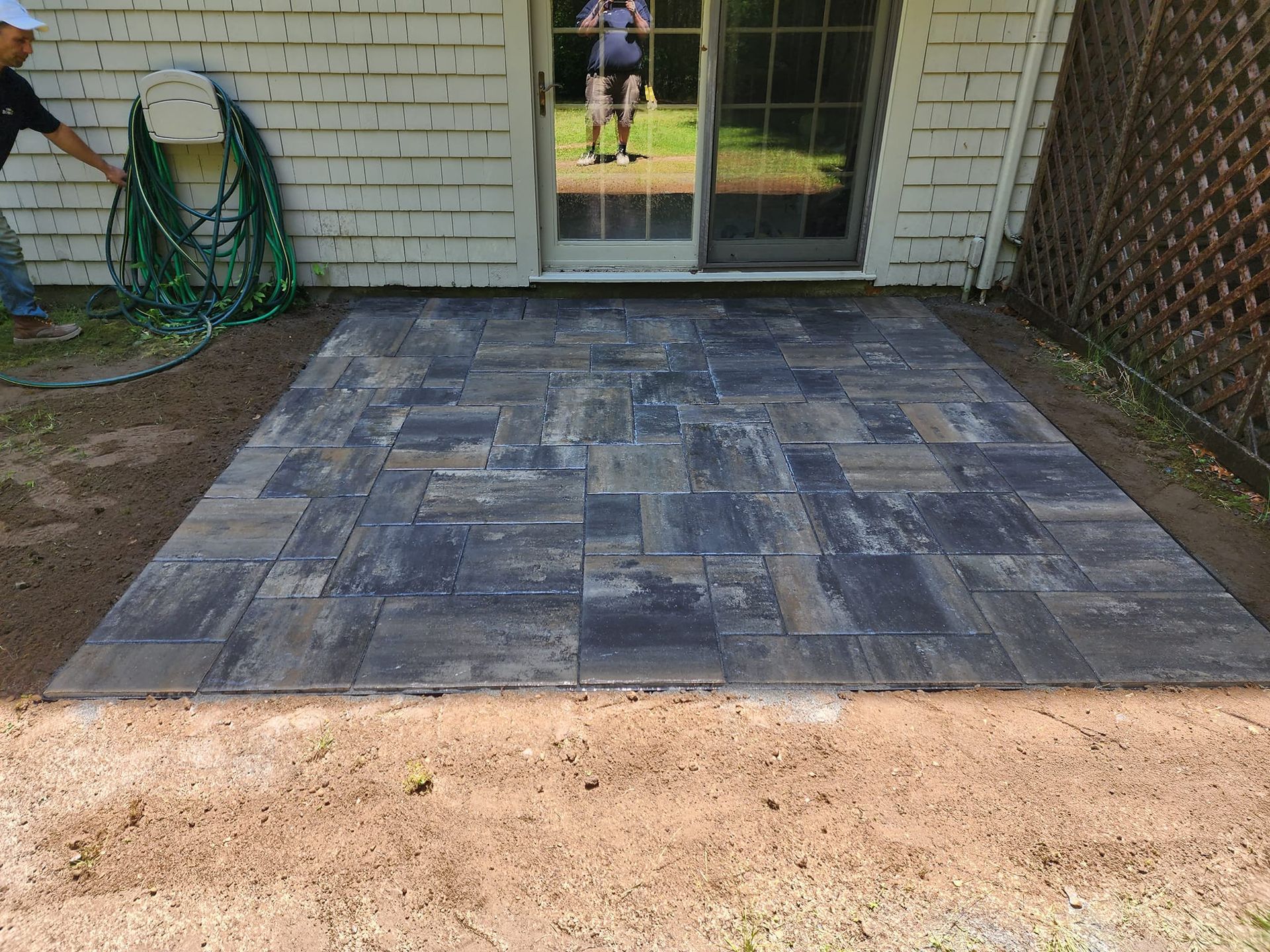 A man is working on a patio in front of a house.