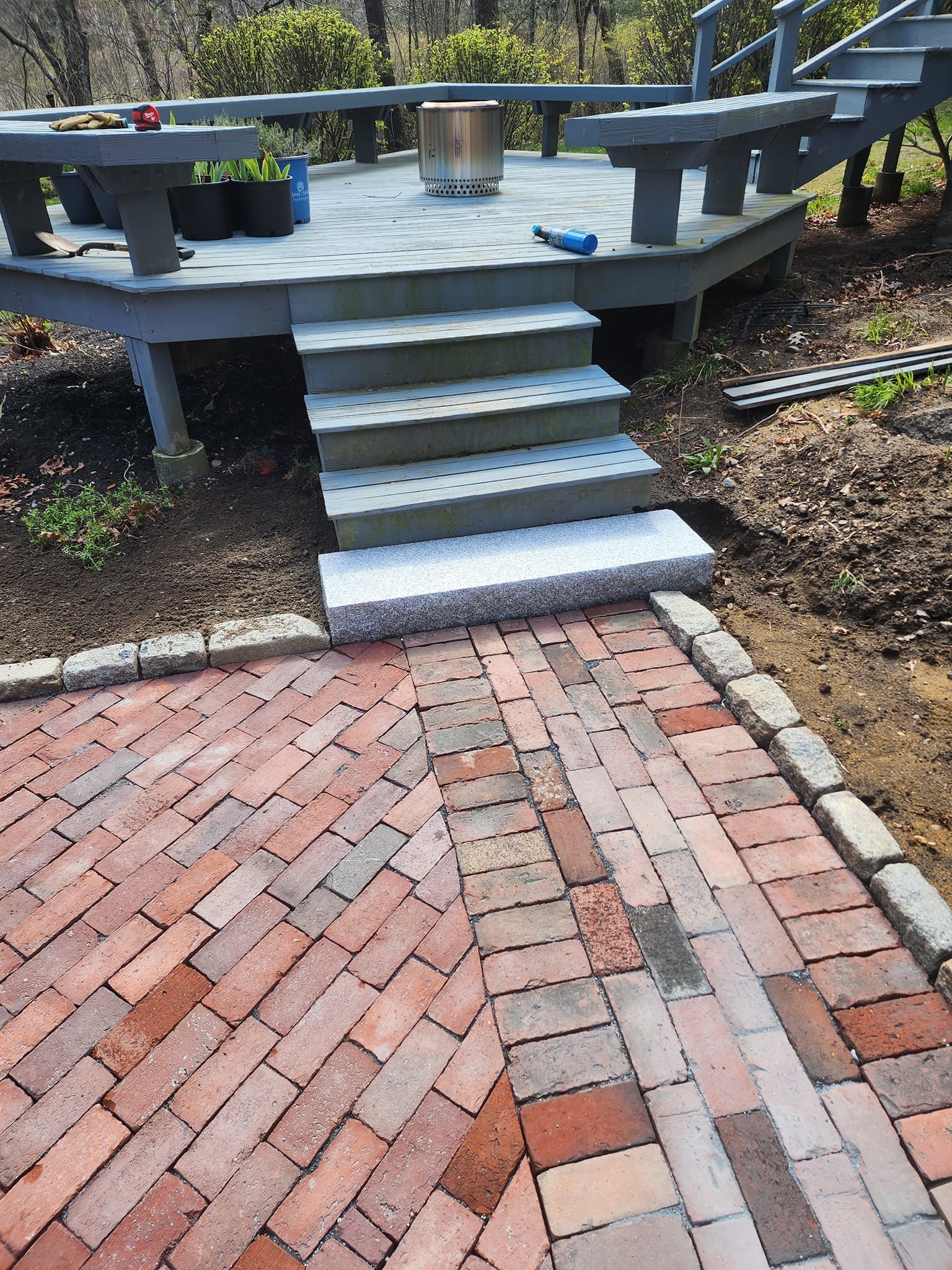 A brick walkway leading to a wooden deck with stairs.