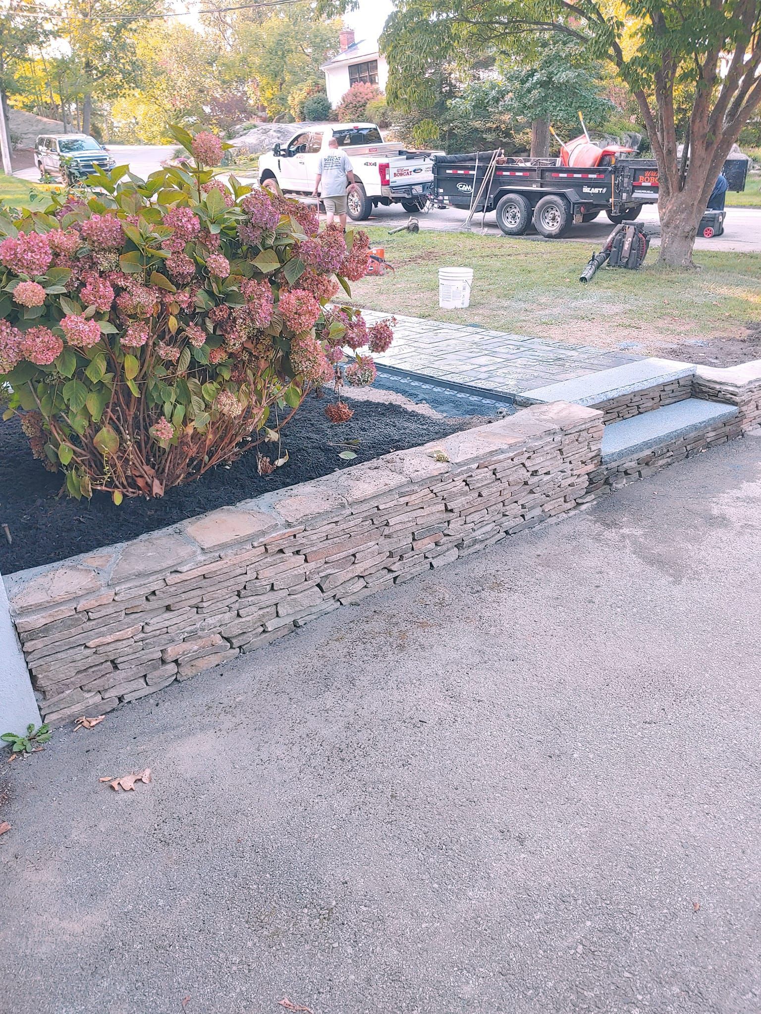 A truck is parked in a driveway next to a stone wall.