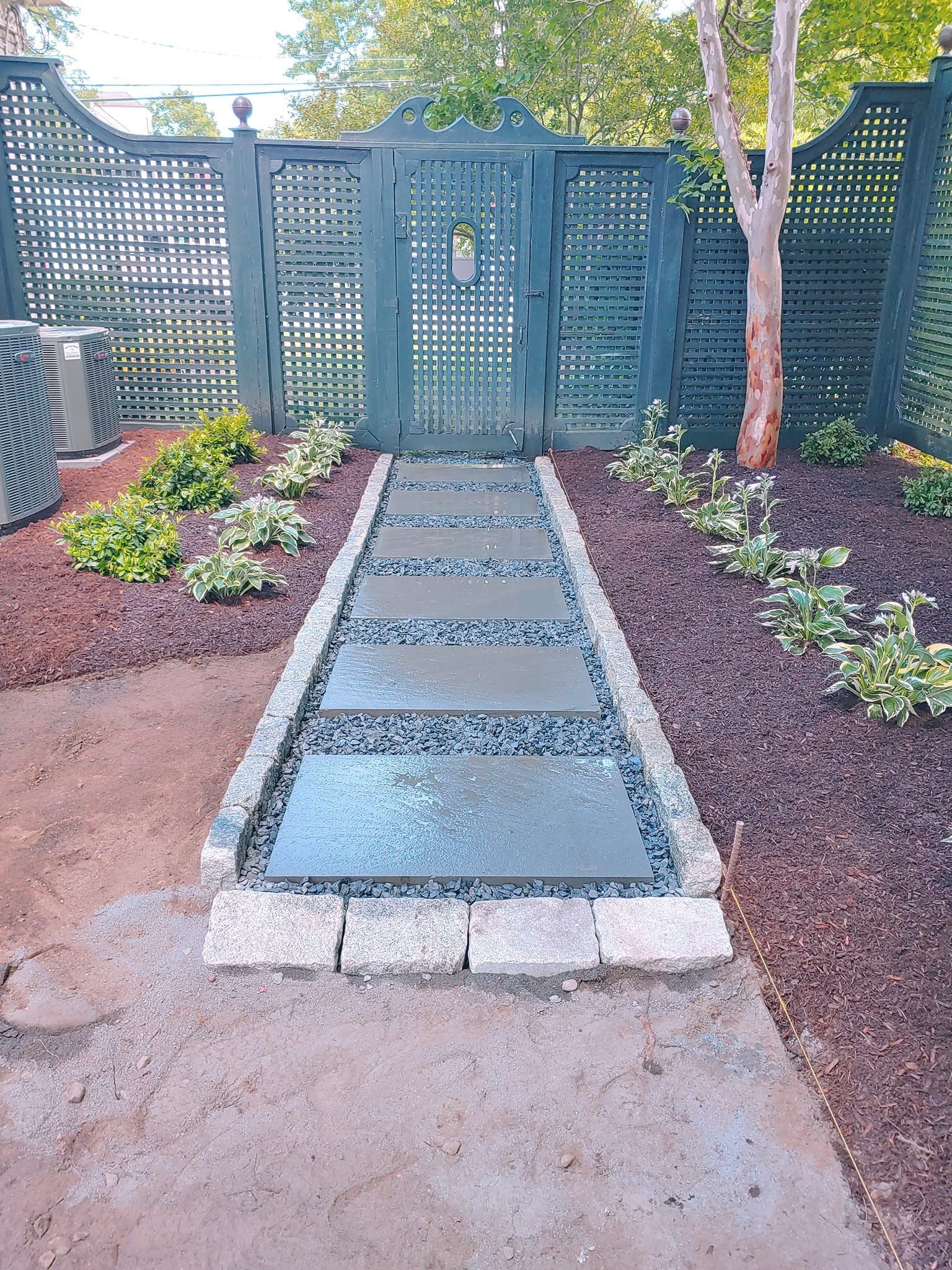 A stone walkway leading to a gate in a garden.