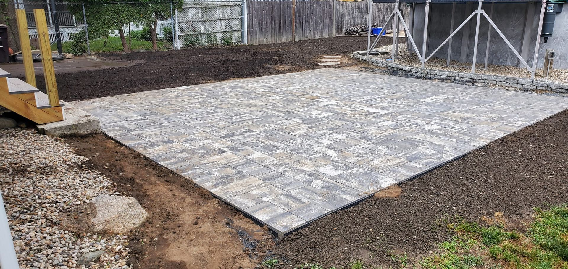 A patio is being built in the backyard of a house.