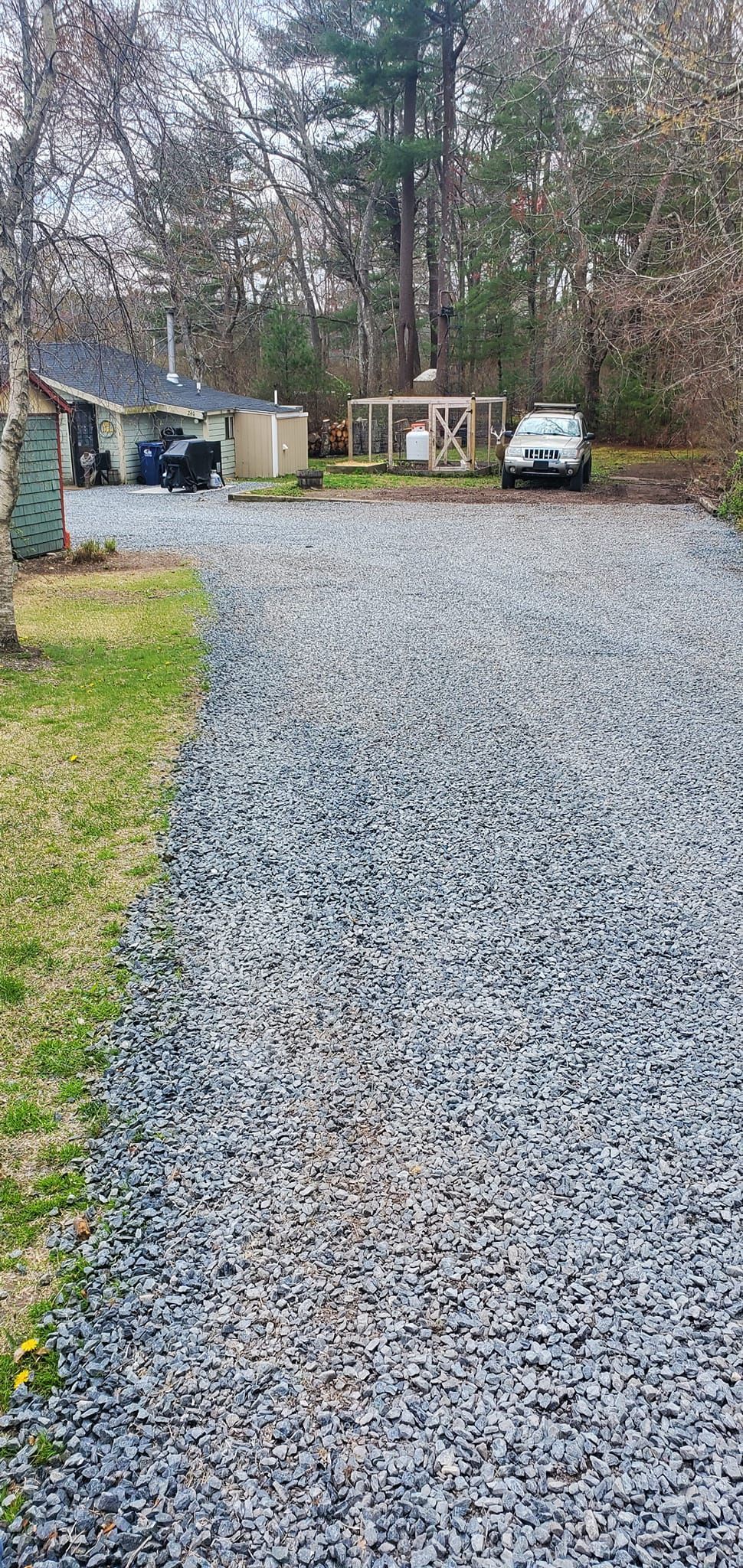 A gravel driveway leading to a house with a car parked on the side of it.