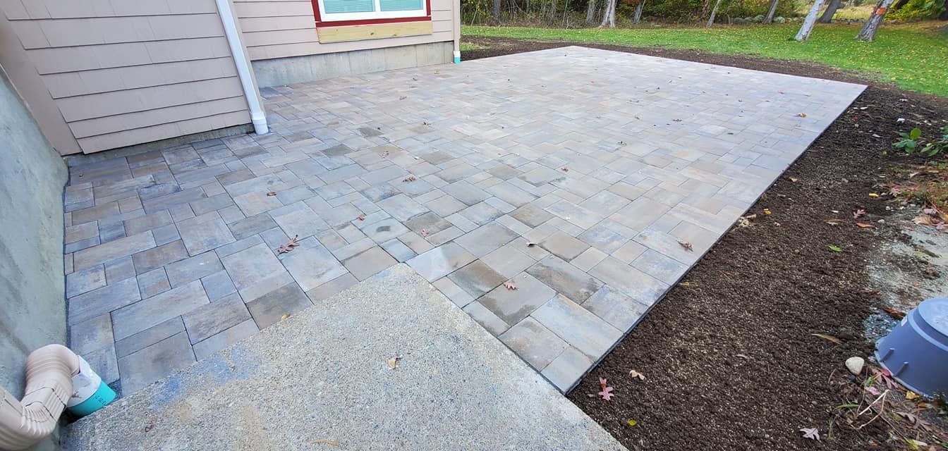 A patio is being built in the backyard of a house.