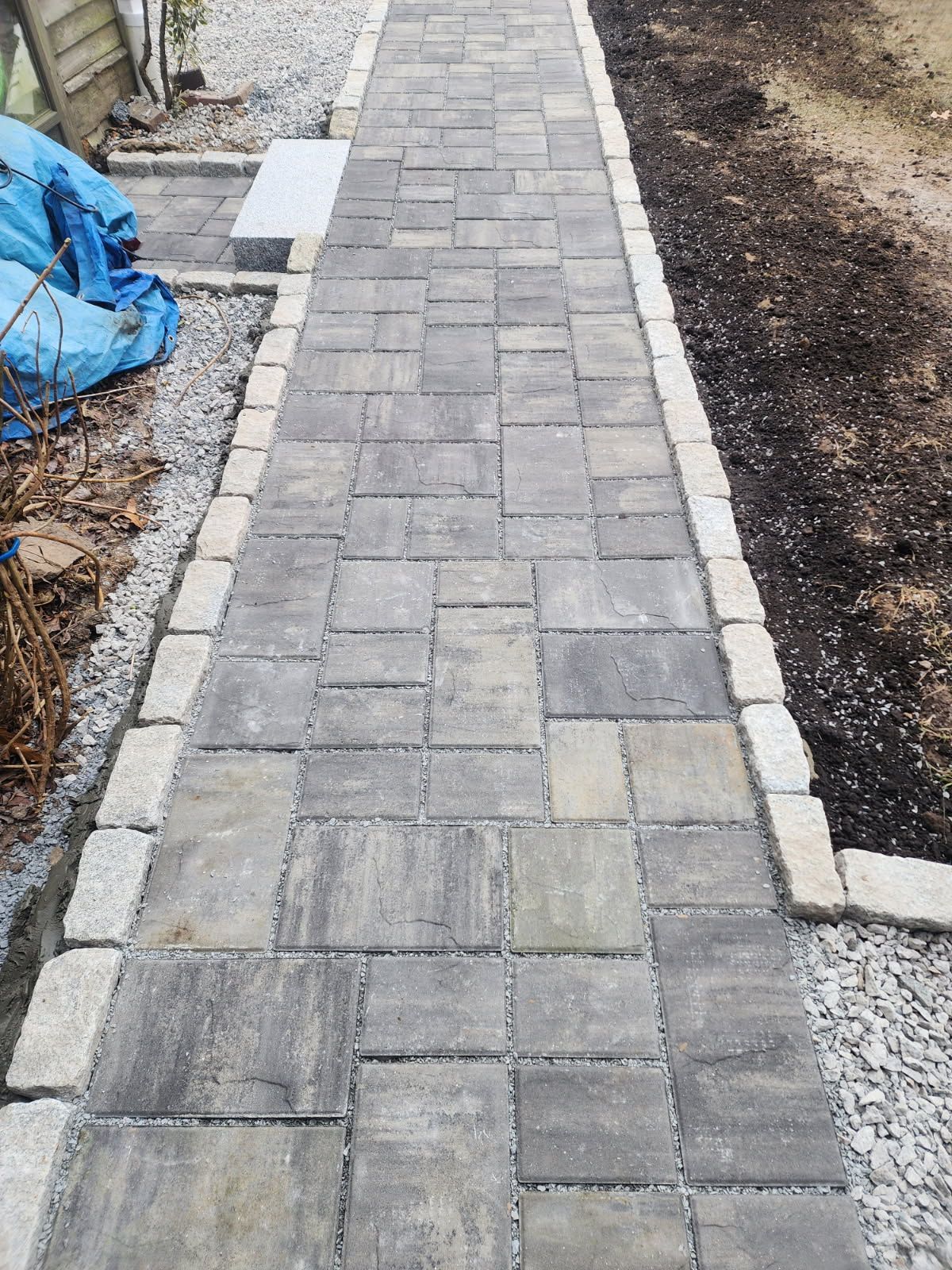 A brick walkway is being built in a backyard.
