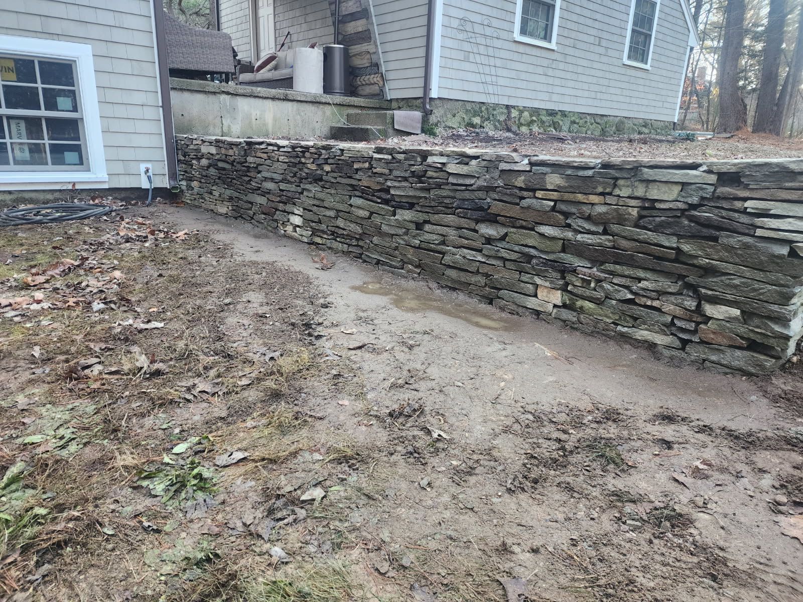 There is a stone wall in front of a house.