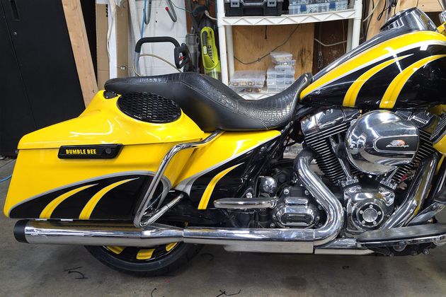 Yellow and black custom motorcycle with chrome exhaust in a garage