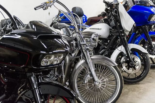 Row of custom motorcycles in a showroom, including a black bike in front and blue and silver bikes behind.