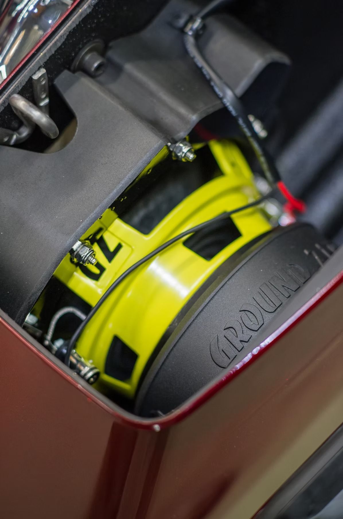 Yellow toy car secured in a red metal case with black padding, viewed from above