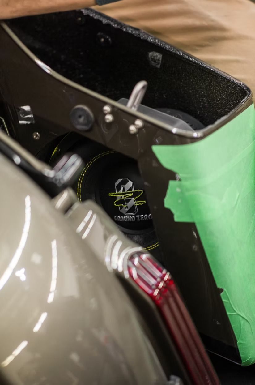 Close-up of a black metal bracket with green tape and a red-striped cable attached.