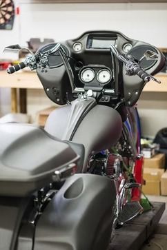 Black motorcycle cockpit and seat in a garage, front view with handlebars and gauges