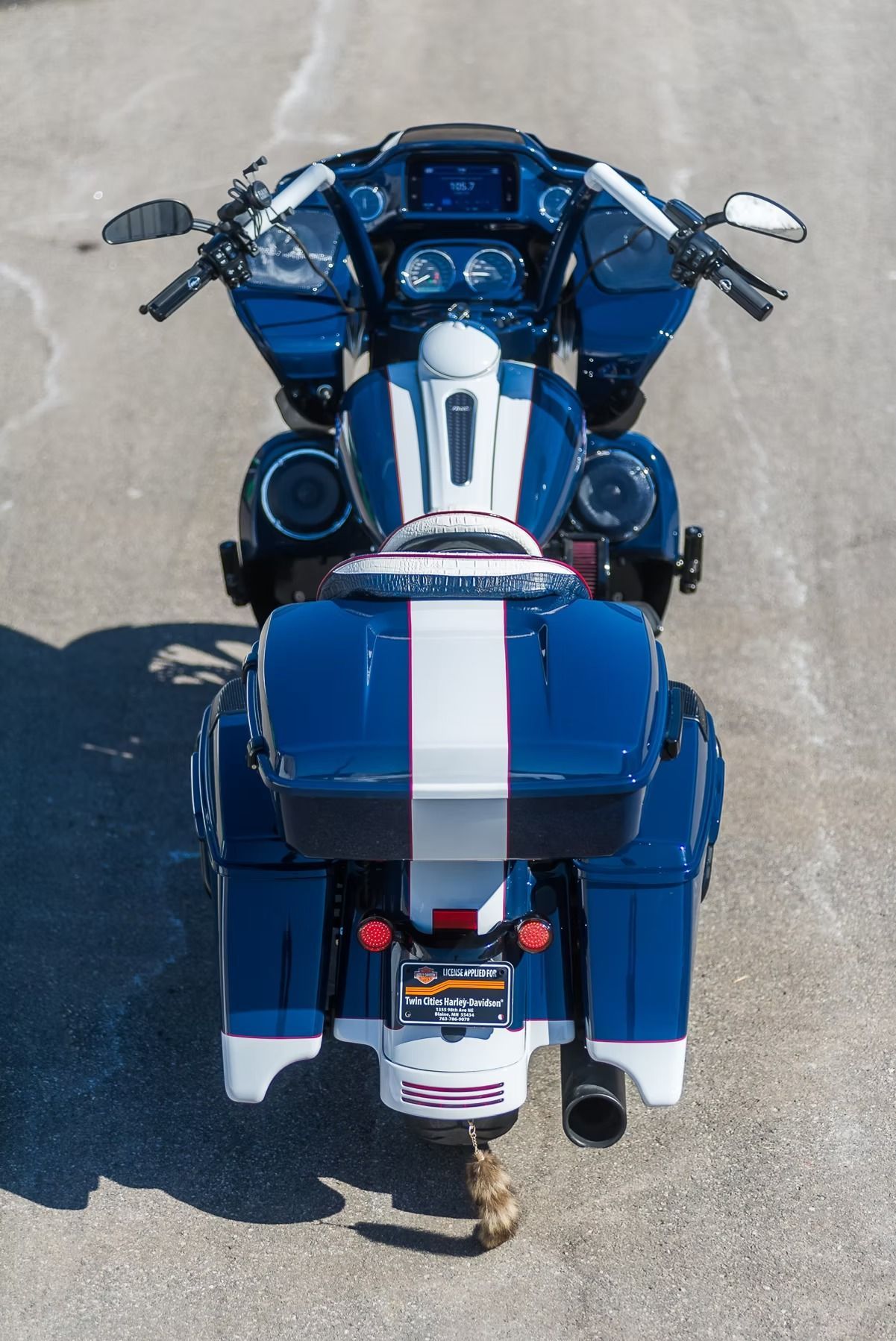 Blue motorcycle viewed from above with white racing stripe parked on pavement