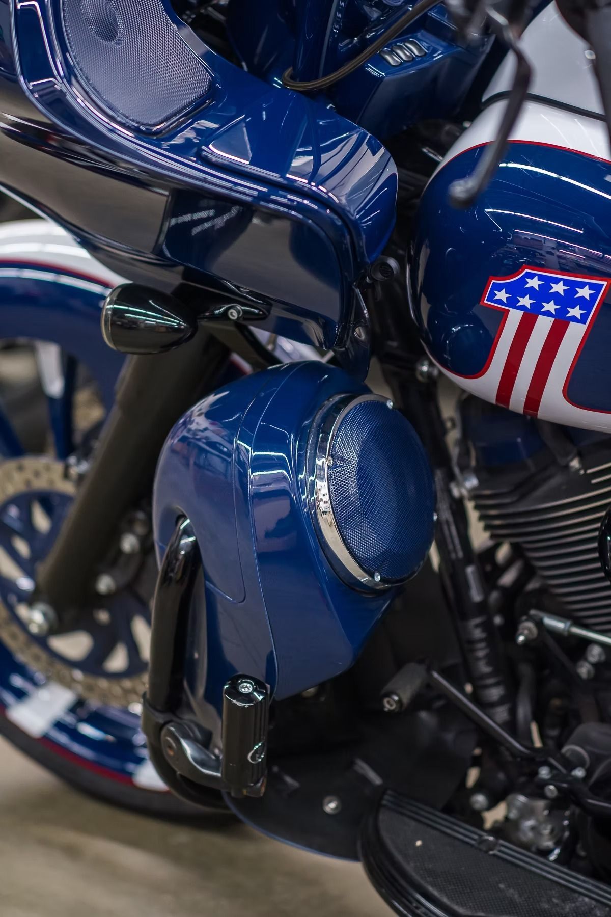 Close-up of a blue motorcycle with chrome details and an American flag tank emblem