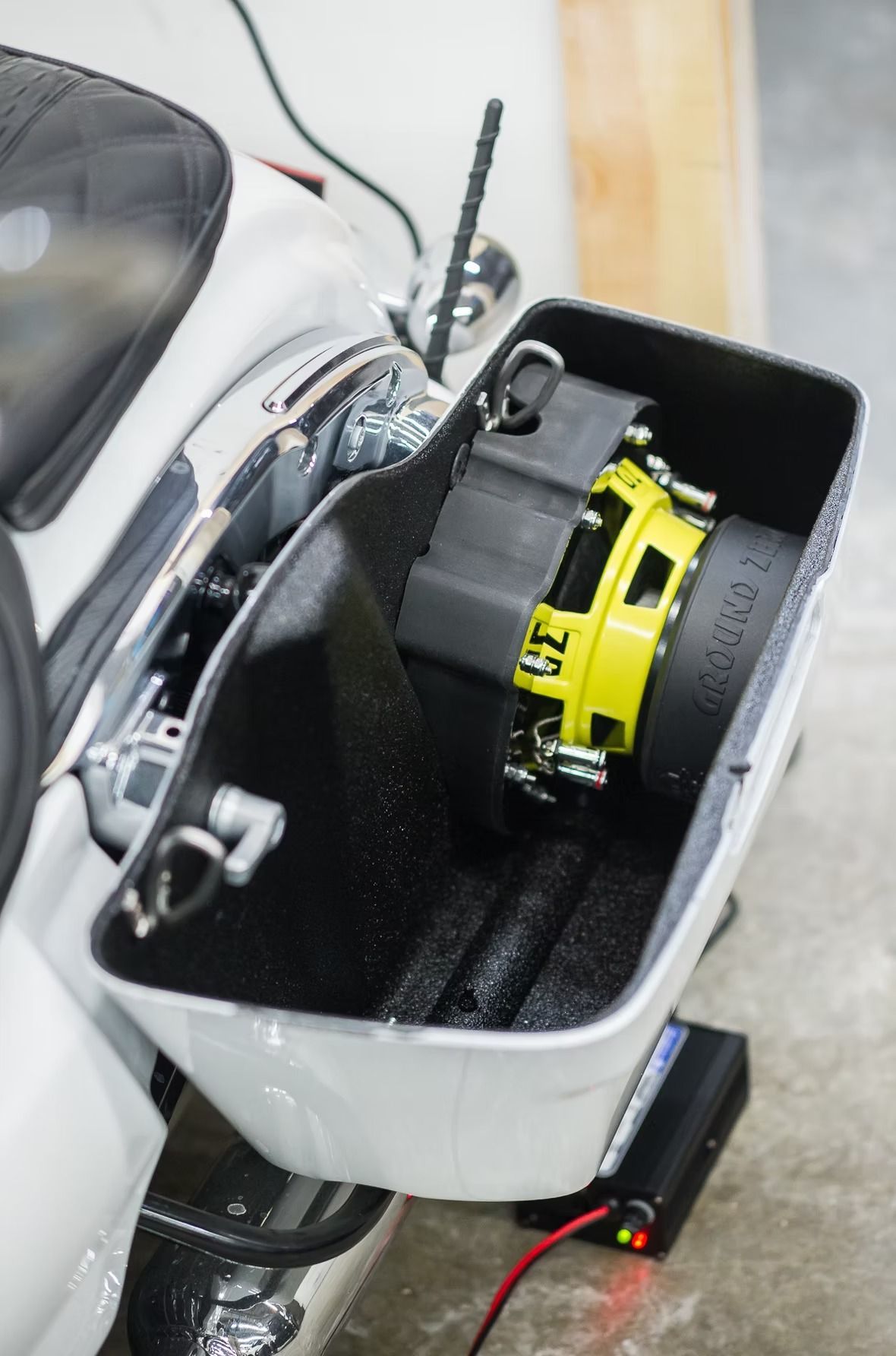 Close-up of a motorcycle’s open storage compartment with a yellow tool or device inside