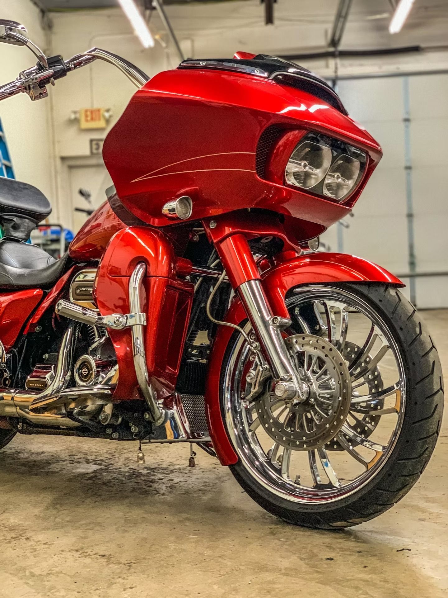 Red custom touring motorcycle with chrome wheels parked in a garage.