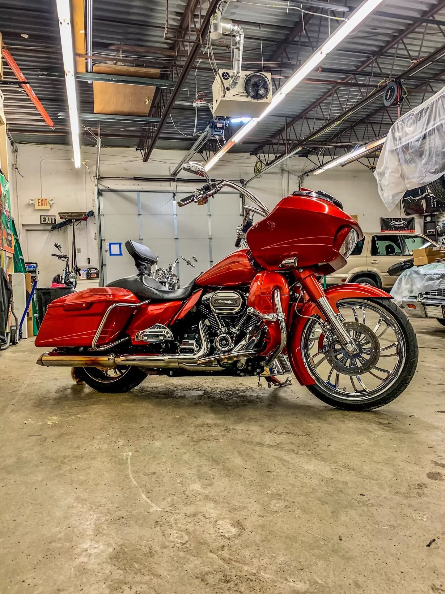 Red touring motorcycle in a garage, side view under industrial ceiling lights.