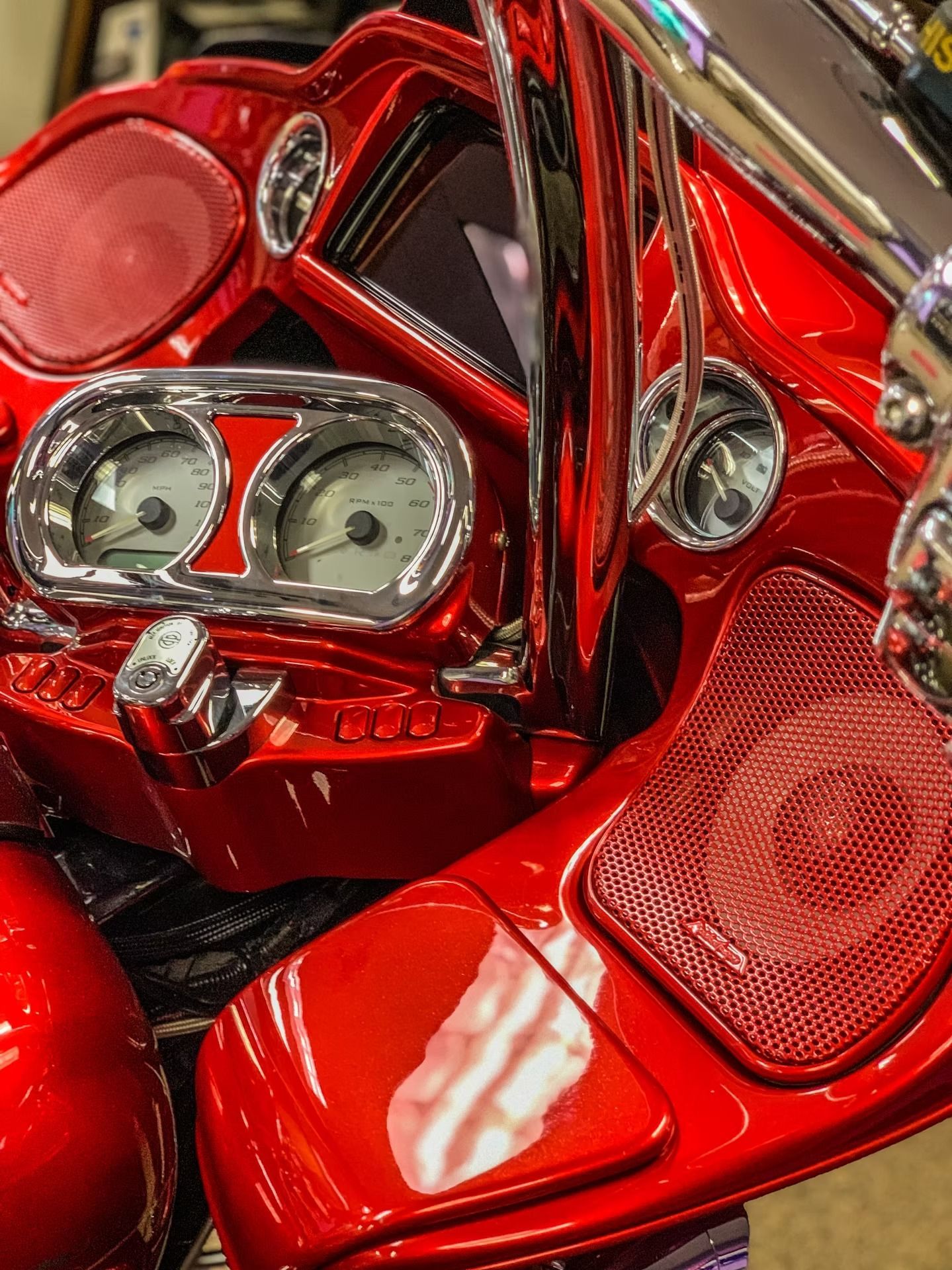 Close-up of a shiny red motorcycle dashboard and seat with chrome details
