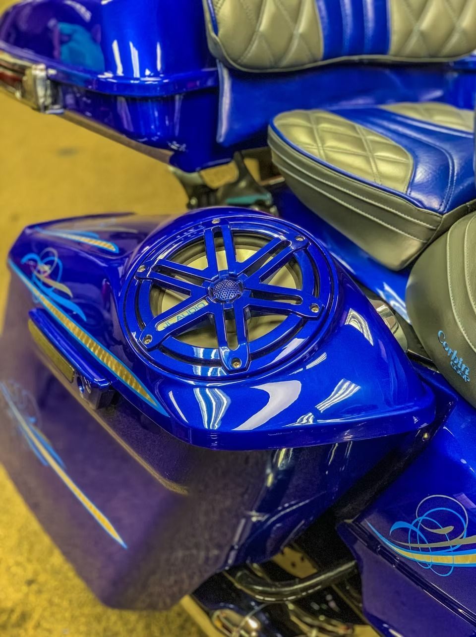 Blue custom motorcycle saddlebag with a built-in round speaker grille and matching seat accents