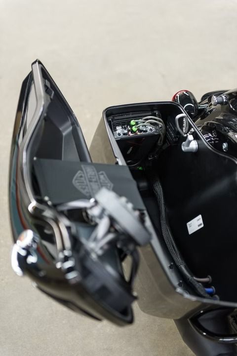 Black motorcycle with side pannier and windshield, parked close-up on a light background