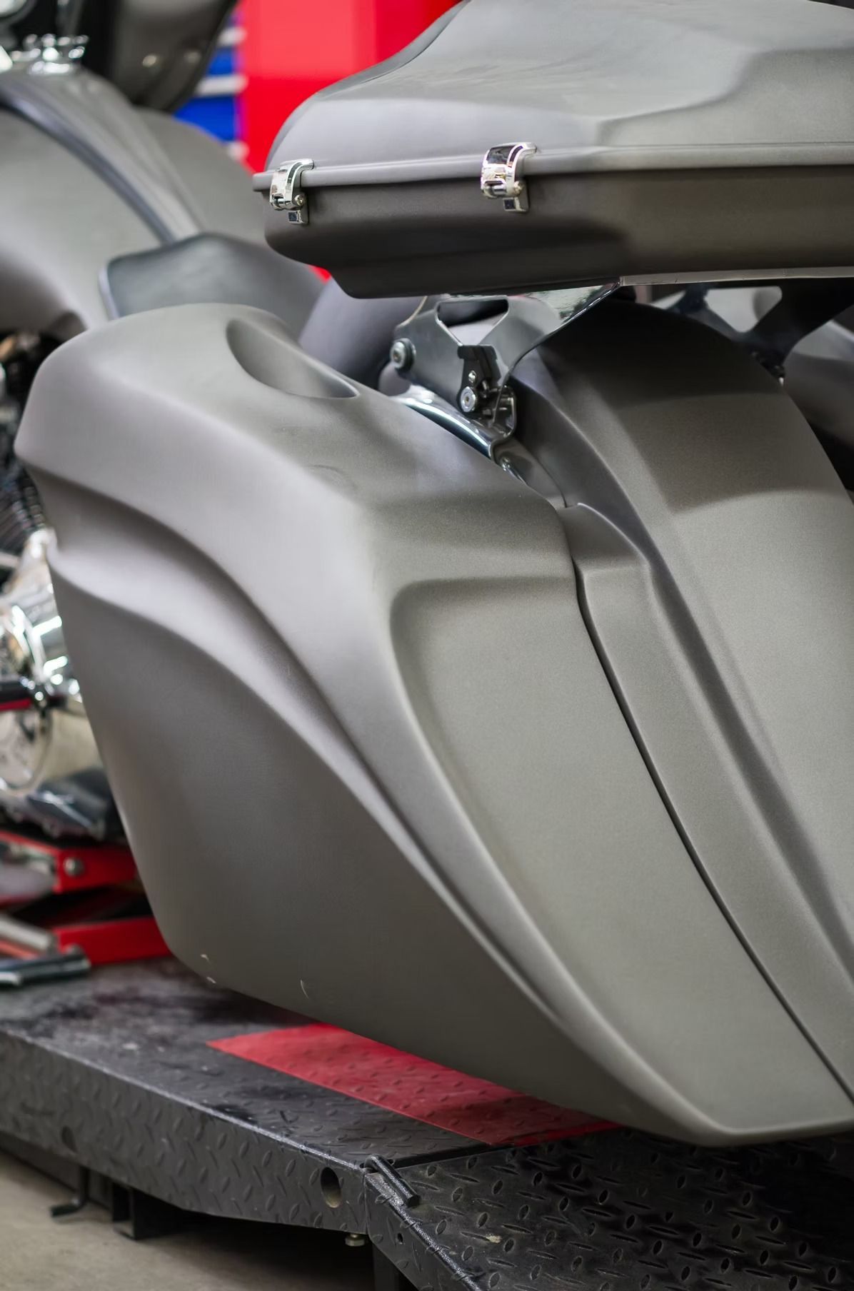 Gray scooter seat and body panels with a top case mounted behind it on a platform