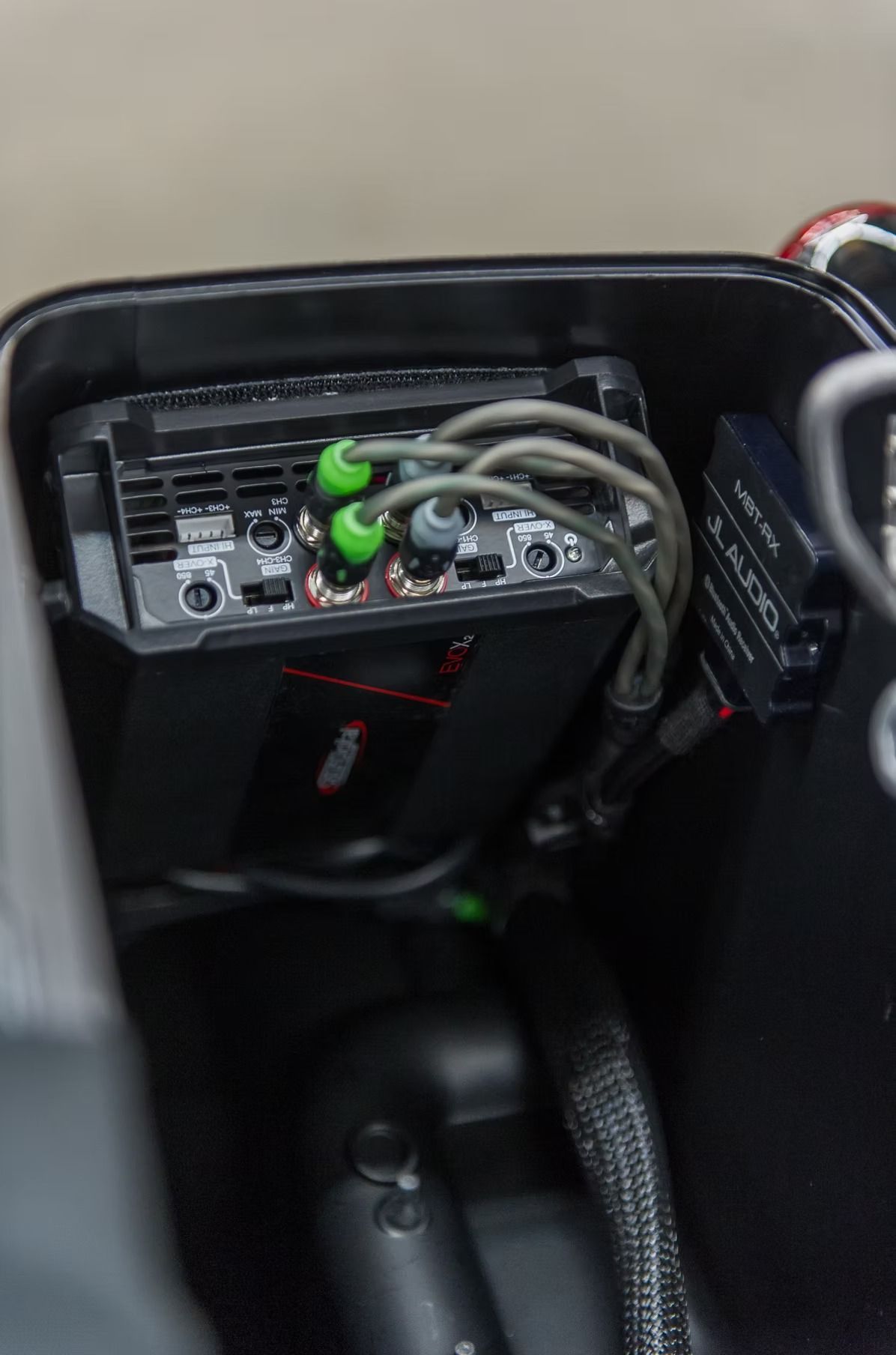 Car dashboard panel with connected audio cables and green plugs beside the gear shift