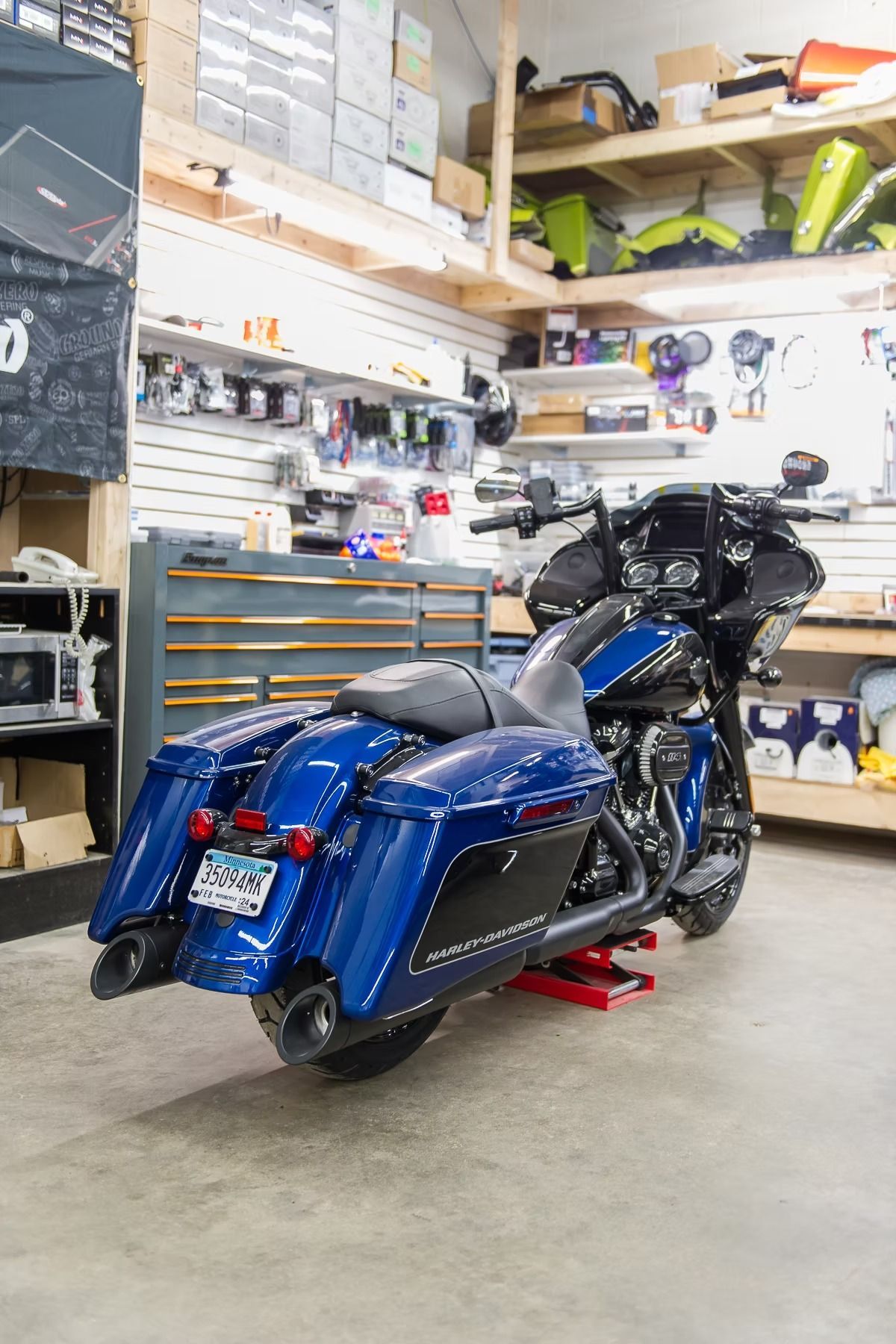 Blue touring motorcycle parked in a garage with shelves and tools in the background