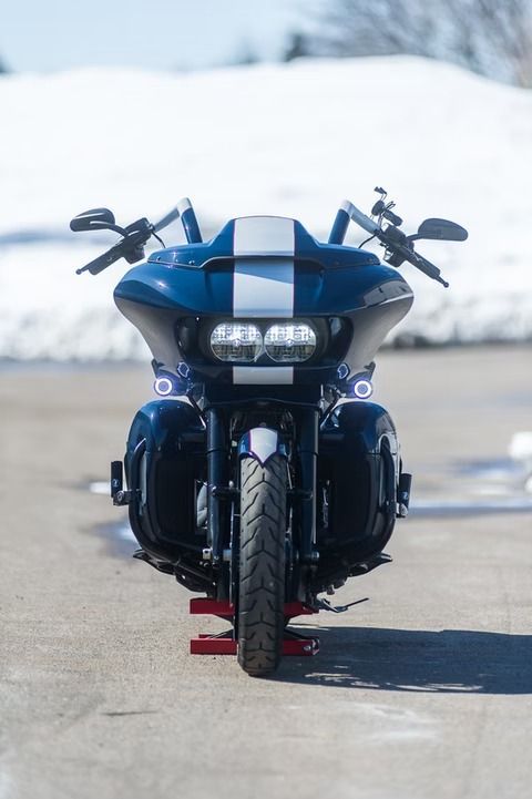 Blue motorcycle with twin white racing stripes, front view on a road with snowy background