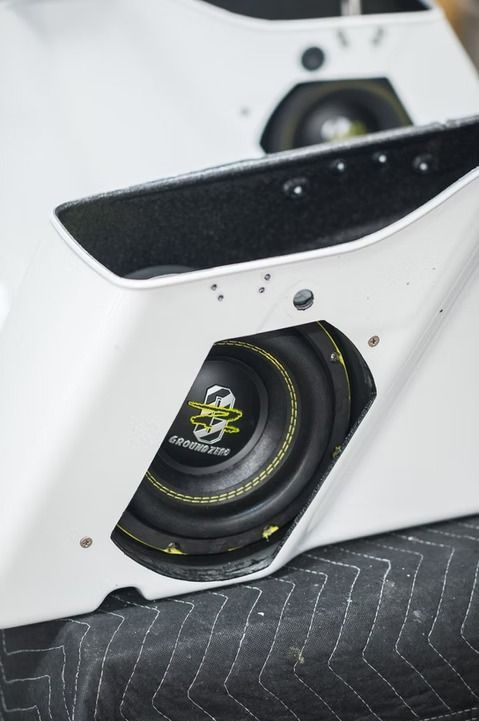 White car door panel with a mounted black speaker and trim cutout