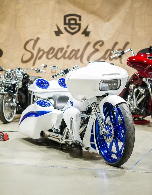 Custom white and blue three-wheeled motorcycle on display at an indoor show, with “Special Eds” backdrop.