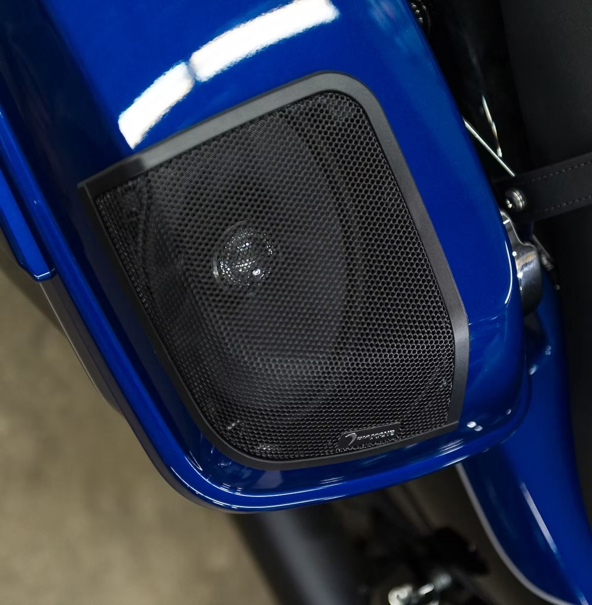 Close-up of a blue motorcycle speaker or grille panel with black mesh.