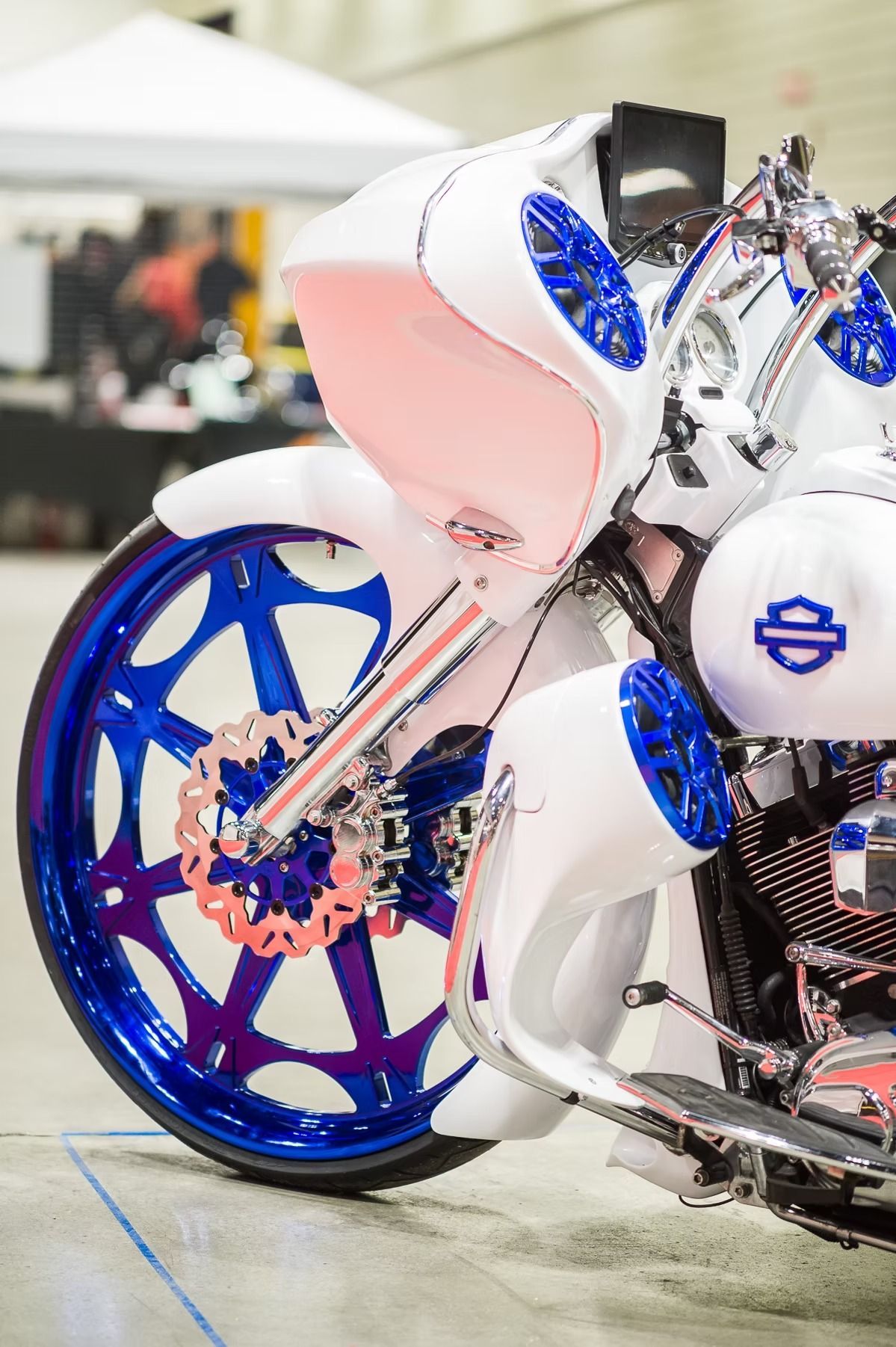 Close-up of a custom white and blue motorcycle wheel and bodywork indoors