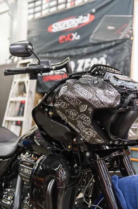 Close-up of a black motorcycle with patterned fairing in a workshop or showroom