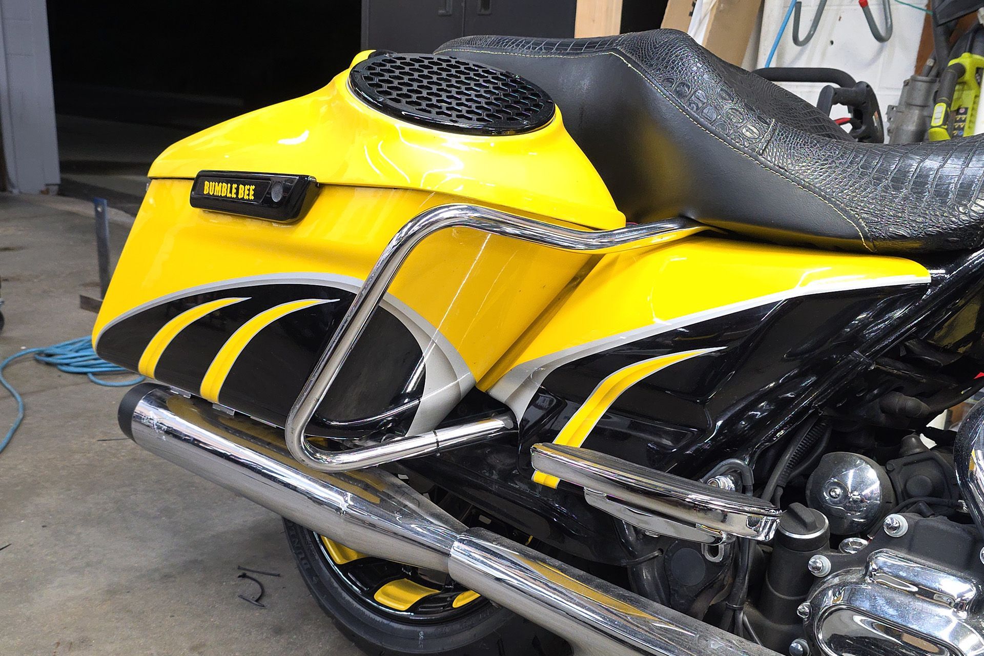 Yellow and black motorcycle with chrome side rails parked in a garage