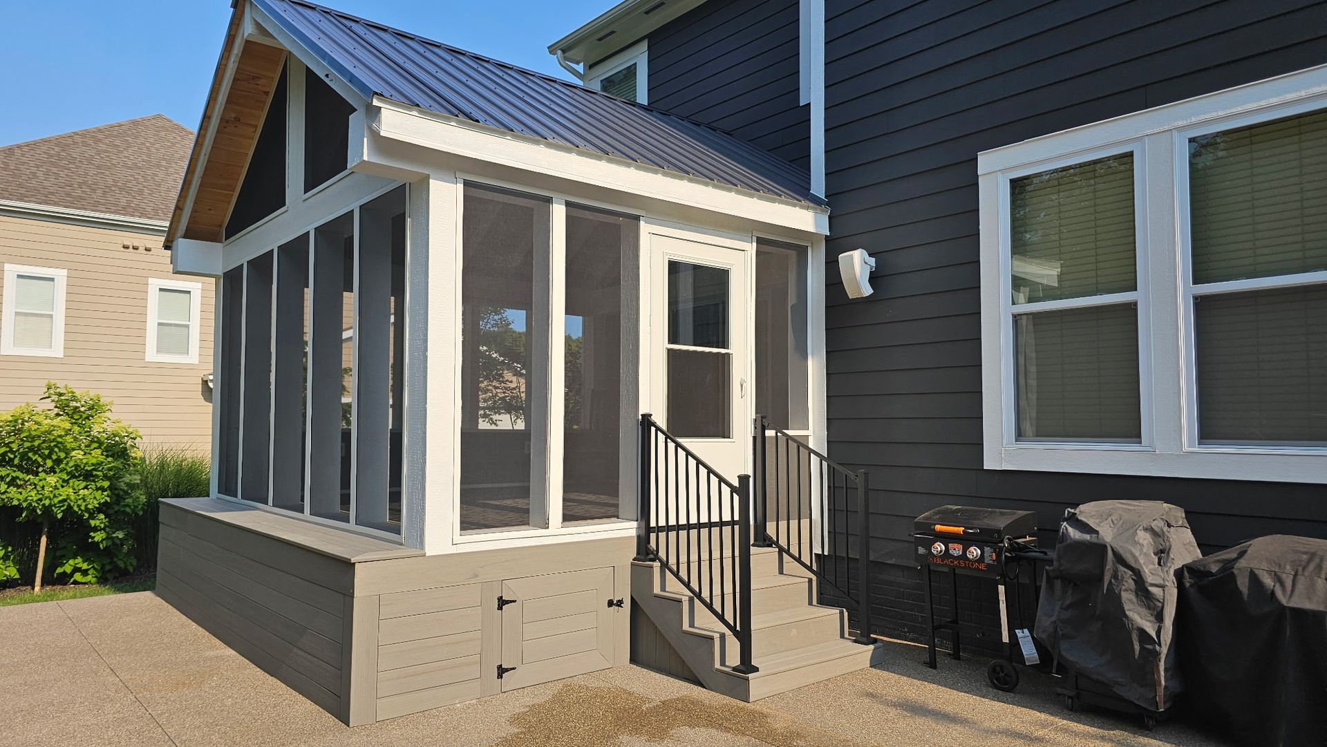A house with a screened in porch and a grill.
