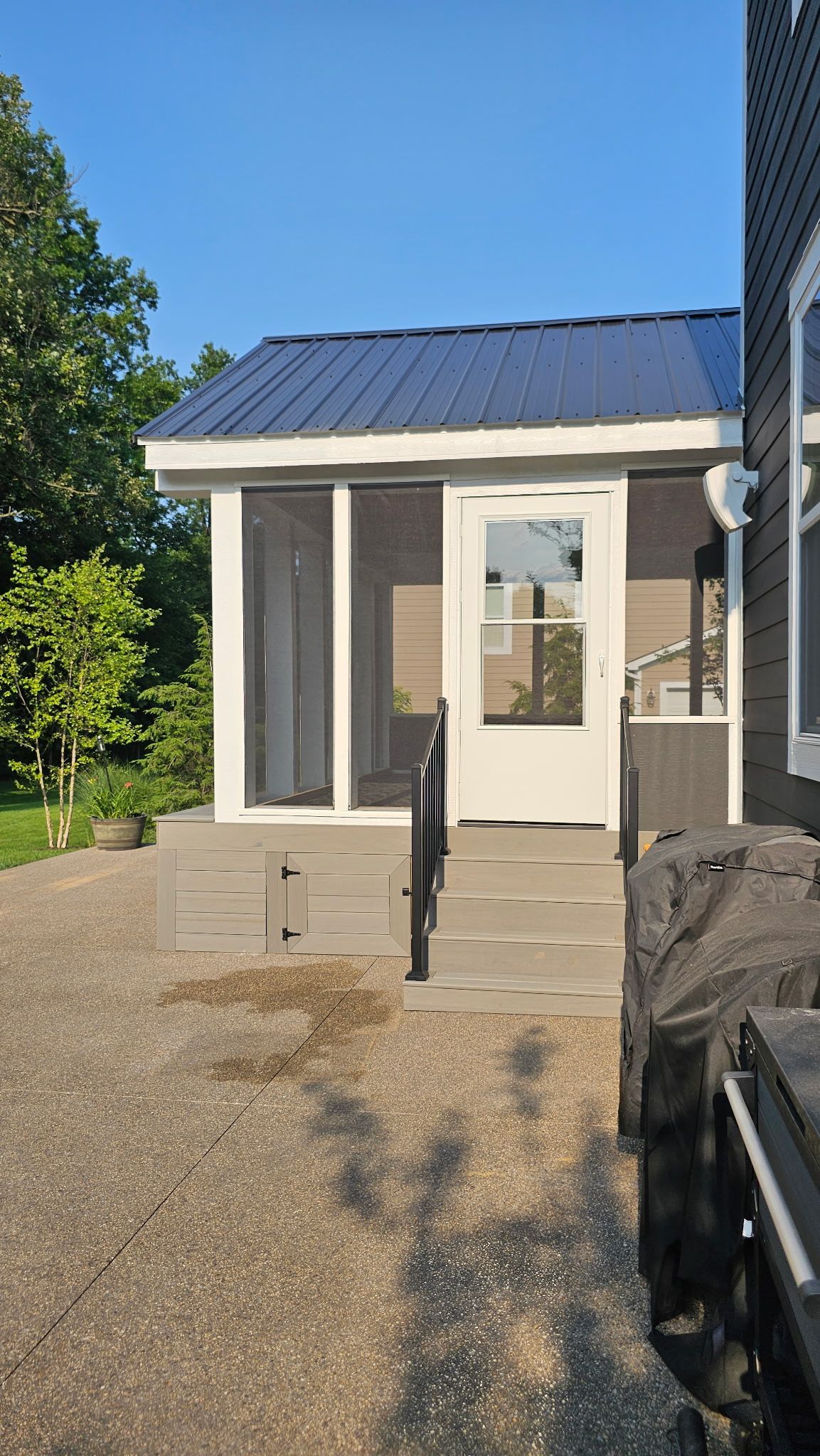 A small house with a screened in porch and stairs.