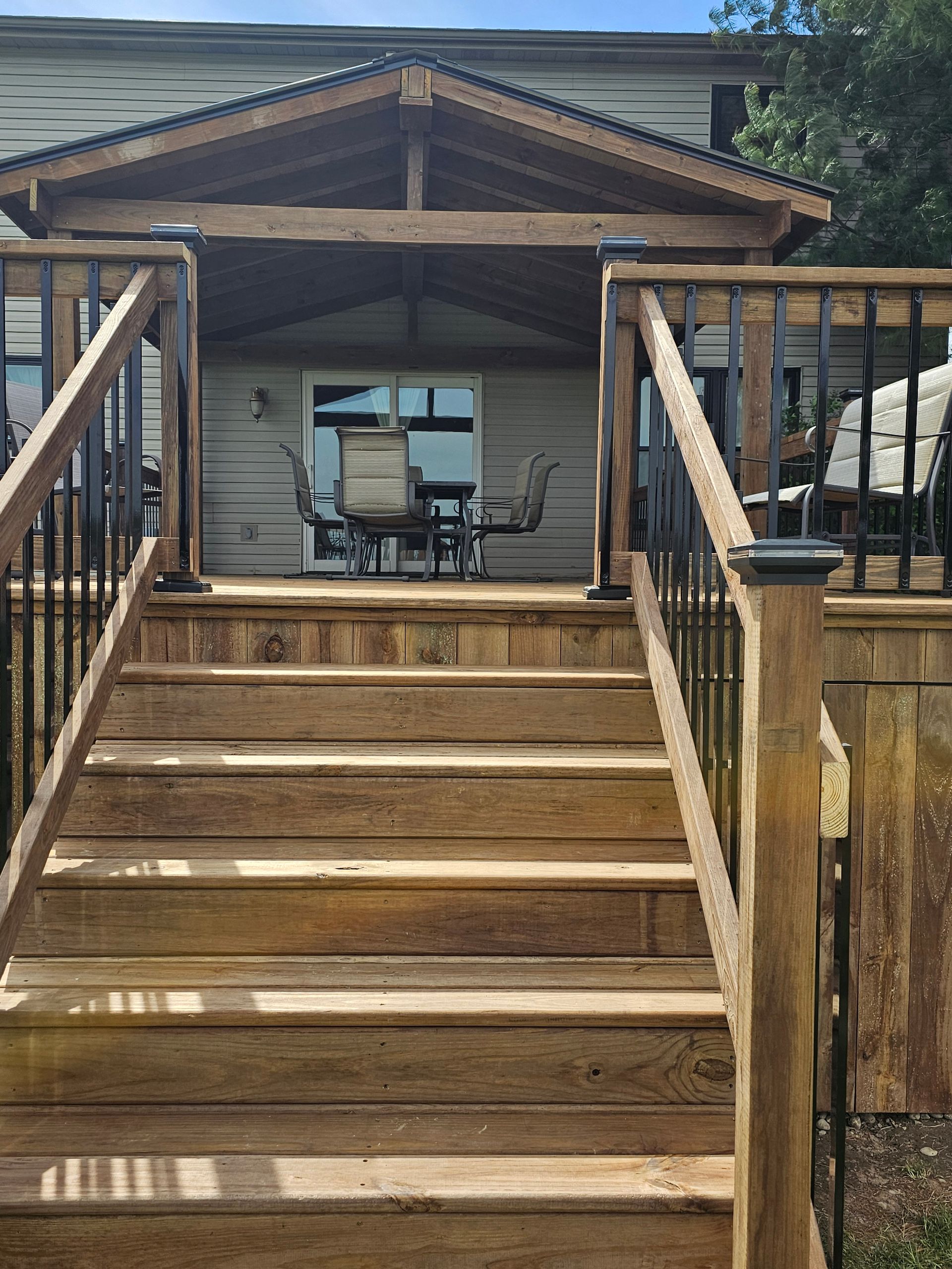 A wooden deck with stairs leading up to it and a table and chairs on it.