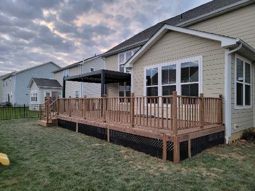 A large wooden deck is in the backyard of a house.