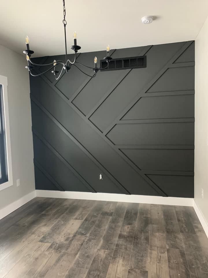 Gray geometric accent wall in a room with hardwood floors and a chandelier.